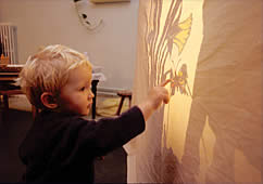a child looking at a shadow on the side of the tent